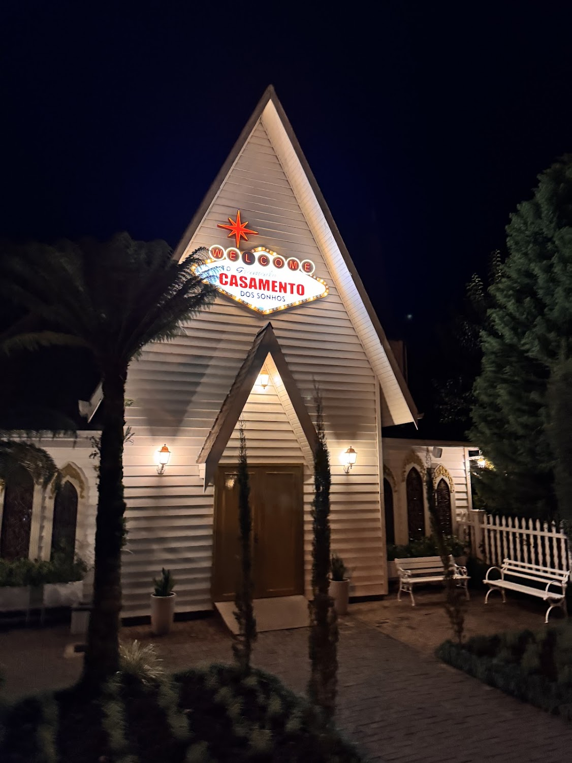 Capela branca com letreiro Casamento dos Sonhos iluminada à noite