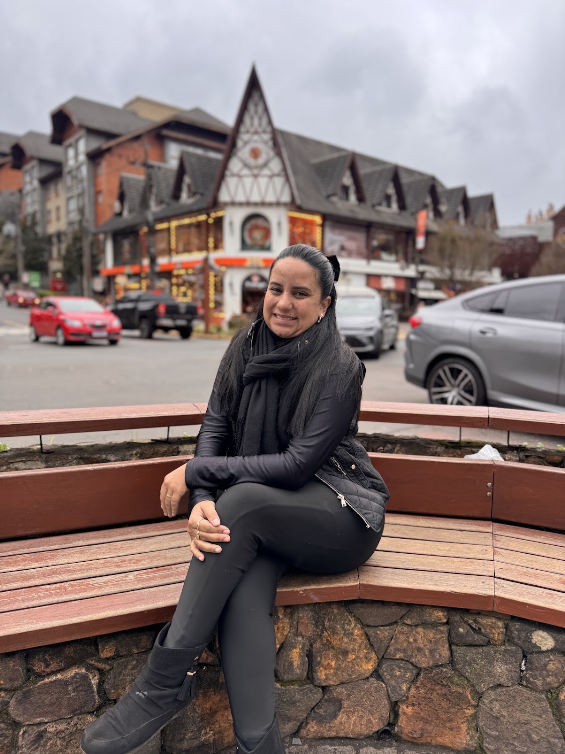 Thamires sentada em um banco de madeira no centro de Gramado
