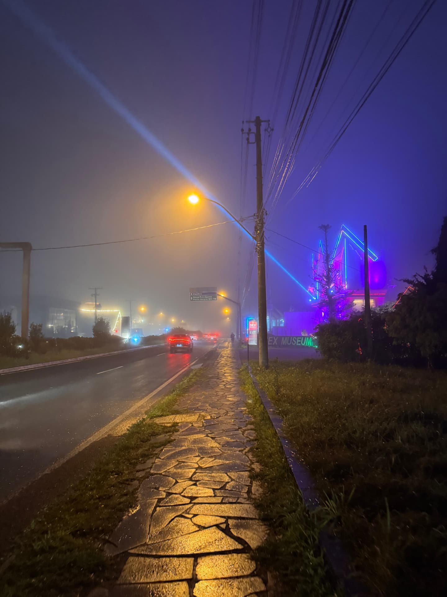 Estrada de Gramado à noite com neblina e luzes coloridas ao fundo