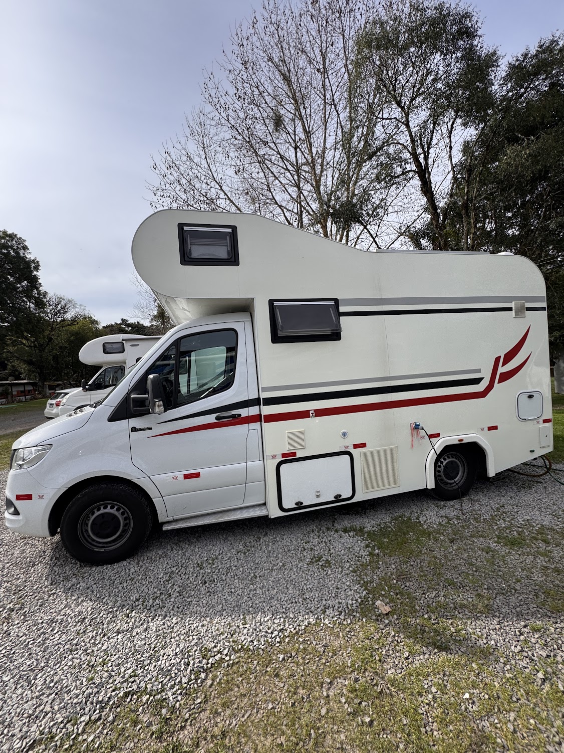 Nosso motorhome branco estacionado em uma área de camping